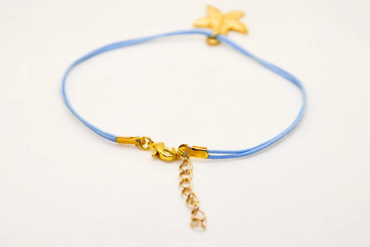 Ankle bracelet with a gold plated starfish dangle charm, blue cord, preppy jewelry